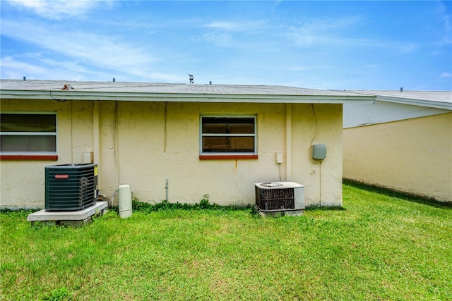 view of side of home with central AC unit and a lawn