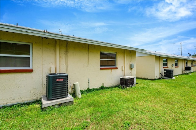 rear view of house featuring central AC and a yard