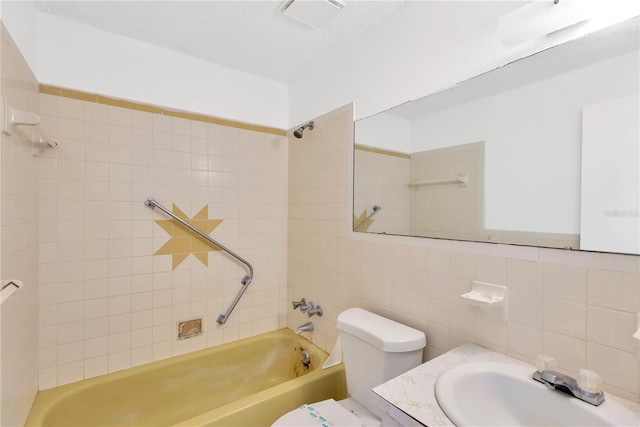 full bathroom featuring tiled shower / bath, tasteful backsplash, tile walls, vanity, and toilet