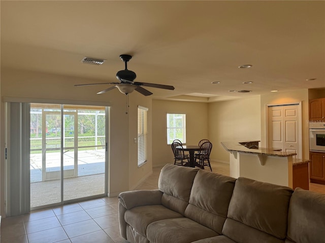 tiled living room featuring ceiling fan and a healthy amount of sunlight