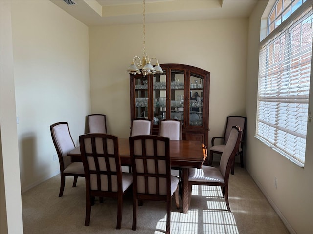 carpeted dining room featuring a raised ceiling and a chandelier