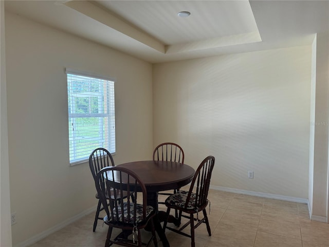 dining area with light tile patterned flooring and a tray ceiling