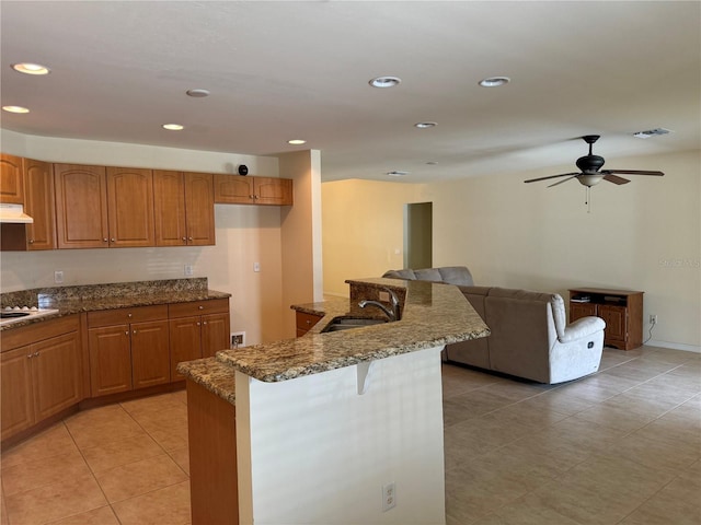 kitchen featuring stovetop, ceiling fan, sink, stone countertops, and light tile patterned floors