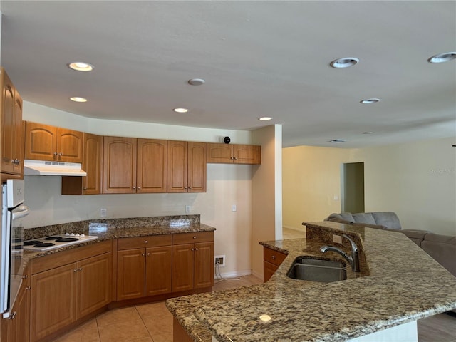 kitchen featuring dark stone countertops, sink, white appliances, and light tile patterned floors