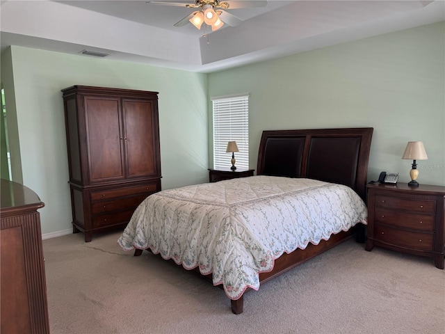 bedroom with ceiling fan, a raised ceiling, and light colored carpet