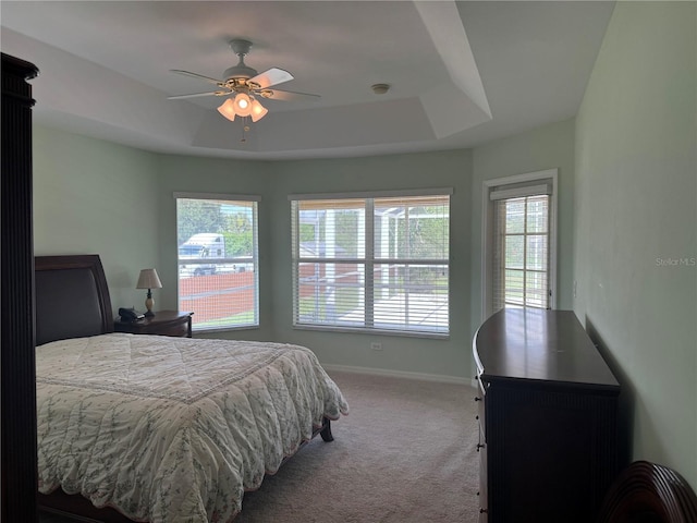 bedroom with ceiling fan, a raised ceiling, and carpet flooring