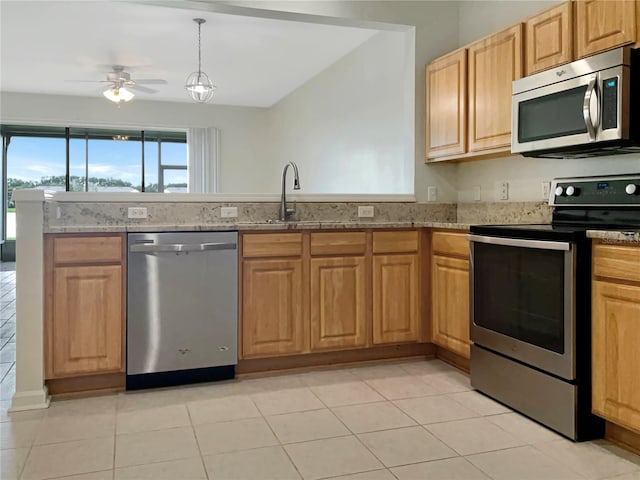 kitchen with appliances with stainless steel finishes, sink, light stone counters, light tile patterned flooring, and ceiling fan