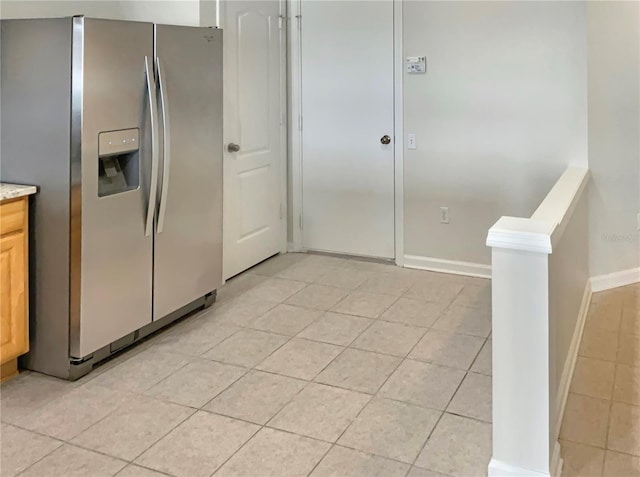 kitchen featuring light brown cabinetry, stainless steel refrigerator with ice dispenser, and light tile patterned floors