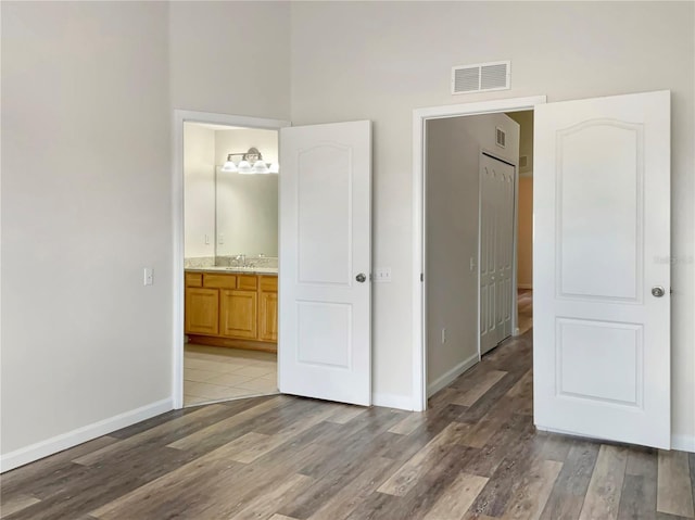 unfurnished bedroom featuring tile patterned flooring, connected bathroom, and sink