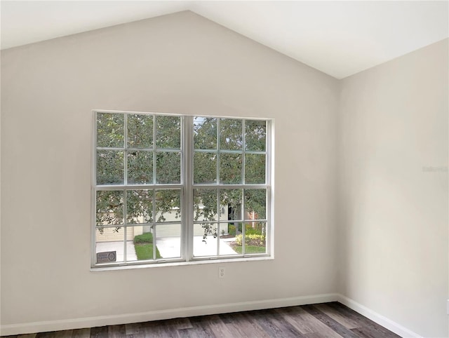 unfurnished room featuring dark wood-type flooring, vaulted ceiling, and a wealth of natural light