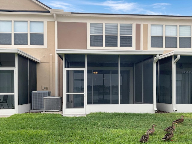 back of house with a yard, a sunroom, and cooling unit