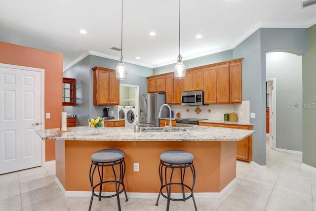 kitchen featuring separate washer and dryer, a kitchen breakfast bar, appliances with stainless steel finishes, light tile patterned floors, and a center island with sink