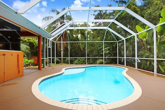 view of swimming pool featuring glass enclosure and a patio