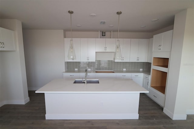 kitchen featuring decorative light fixtures, sink, and an island with sink