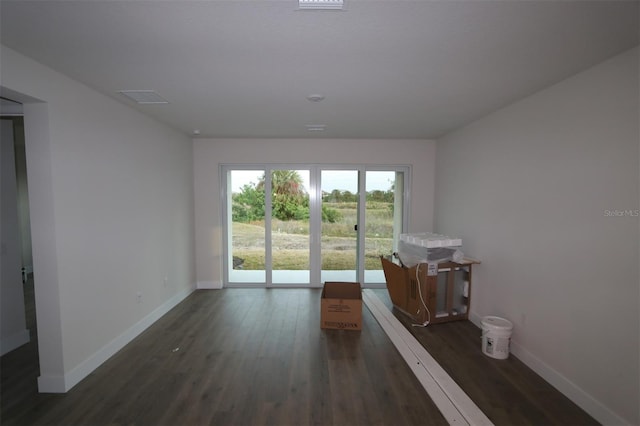 unfurnished room featuring dark wood-type flooring and baseboards