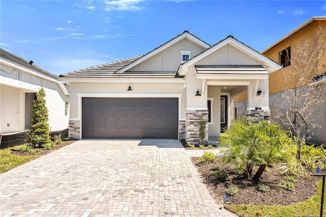 view of front of property with an attached garage, stone siding, decorative driveway, and stucco siding
