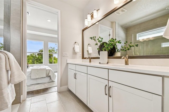 bathroom with a sink, double vanity, tile patterned flooring, and ensuite bath