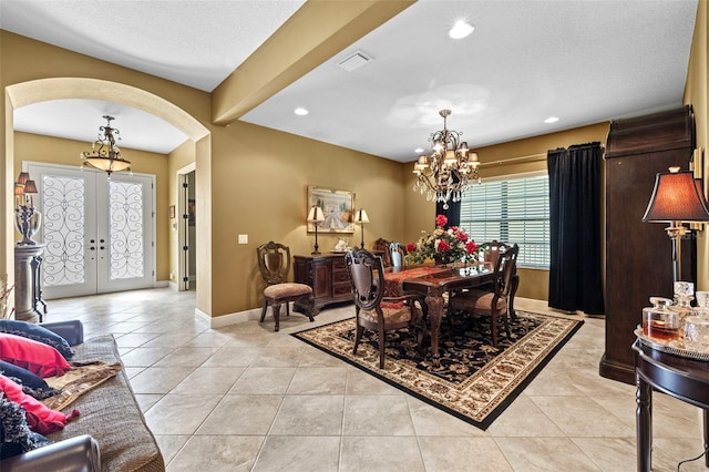 dining space featuring a chandelier, french doors, light tile patterned floors, and a textured ceiling