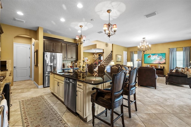 kitchen with a healthy amount of sunlight, appliances with stainless steel finishes, light tile patterned flooring, and a center island with sink