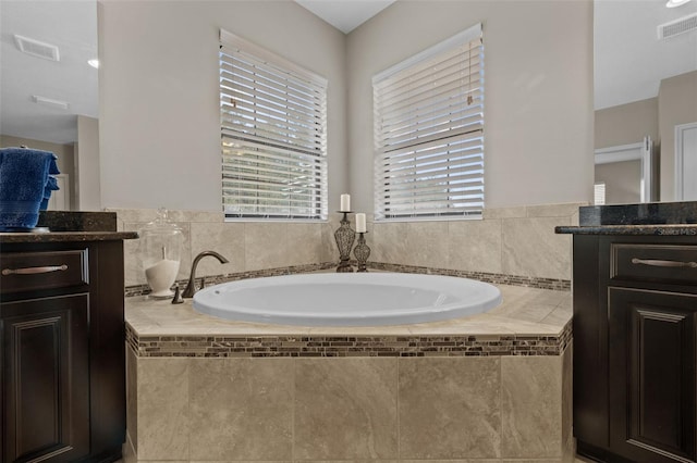 bathroom with vanity and tiled bath