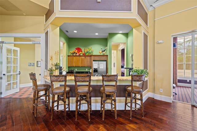 kitchen with a breakfast bar area, stainless steel fridge with ice dispenser, and dark wood-type flooring