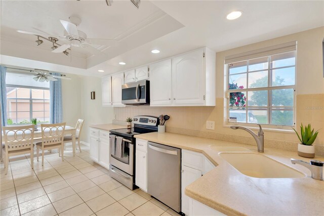 kitchen featuring appliances with stainless steel finishes, a tray ceiling, a healthy amount of sunlight, and white cabinetry