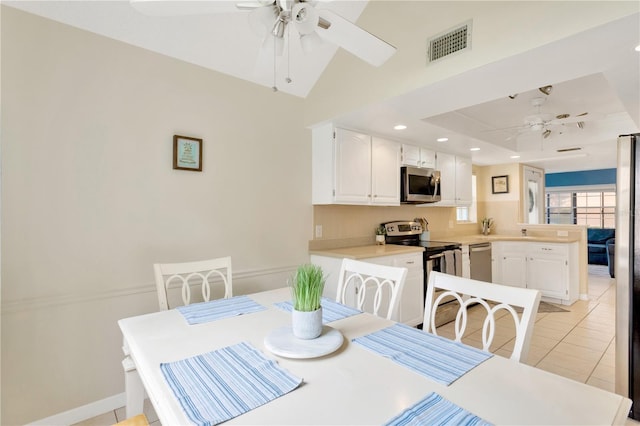 tiled dining space featuring ceiling fan and vaulted ceiling