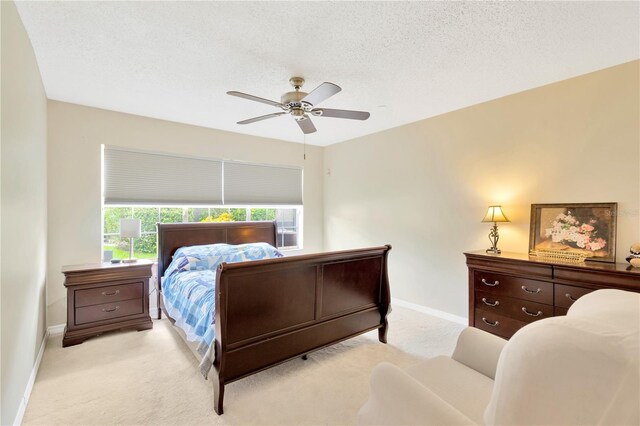 bedroom with light carpet, a textured ceiling, and ceiling fan