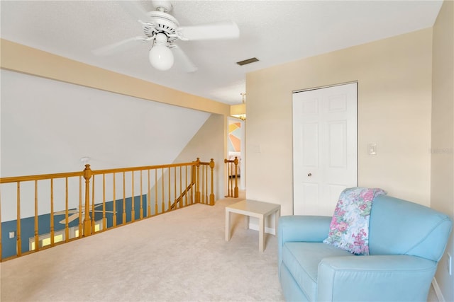 sitting room with carpet flooring, beamed ceiling, and ceiling fan