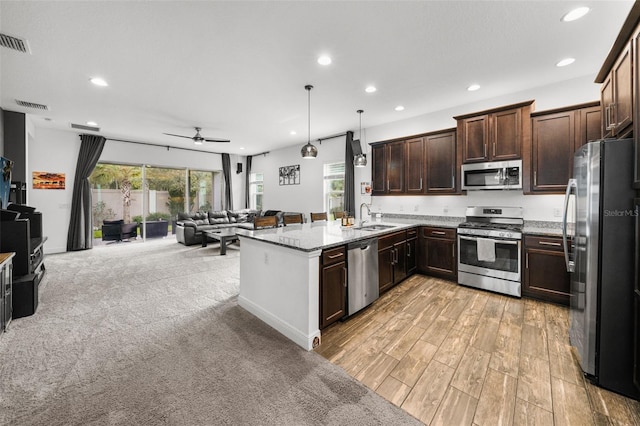 kitchen featuring sink, dark brown cabinets, pendant lighting, stainless steel appliances, and light stone countertops