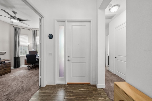 foyer entrance with ceiling fan and dark colored carpet