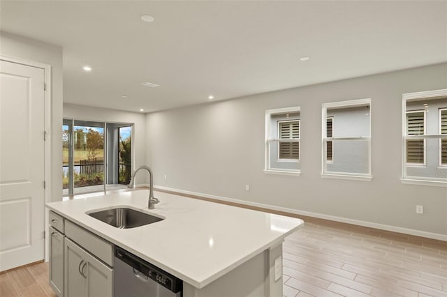 kitchen with sink, dishwasher, and a center island with sink