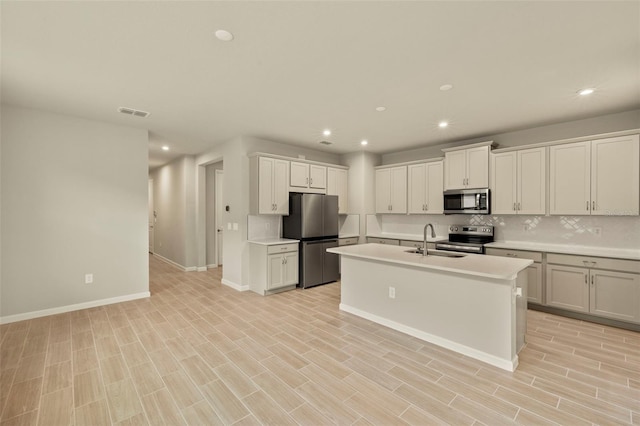 kitchen with sink, white cabinetry, a center island with sink, stainless steel appliances, and decorative backsplash