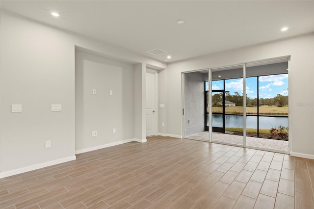 spare room with a water view and light hardwood / wood-style flooring