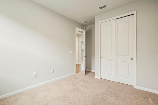 unfurnished bedroom with light colored carpet and a closet