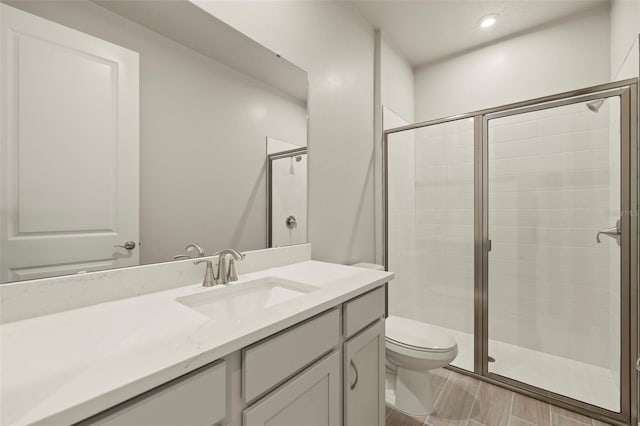 bathroom with vanity, a shower with shower door, and toilet