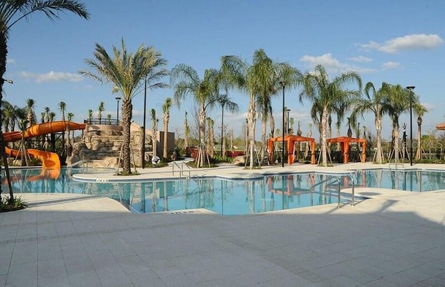 view of pool featuring a water slide and a patio