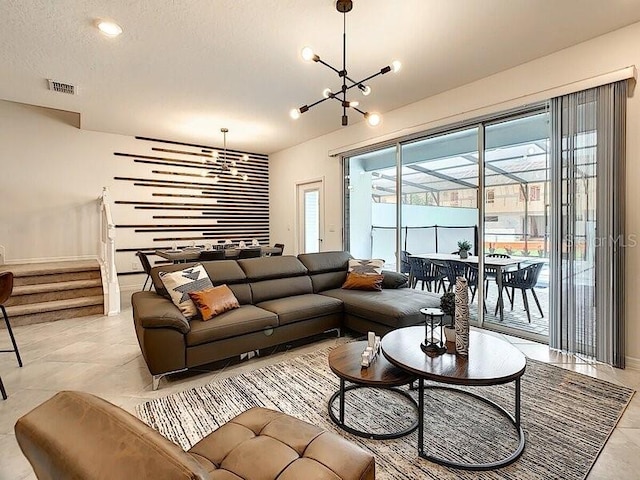 living room with light tile patterned floors, plenty of natural light, an inviting chandelier, and a textured ceiling