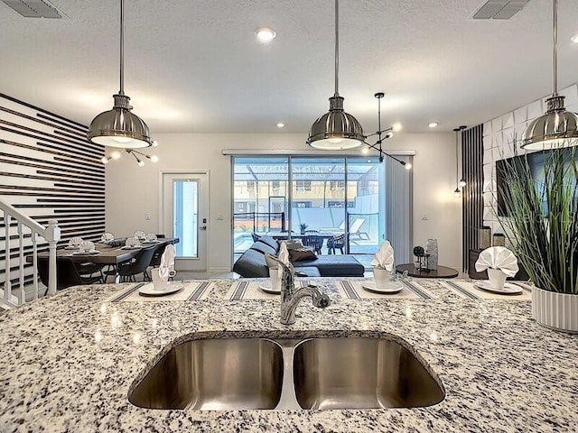 kitchen with a textured ceiling, pendant lighting, and sink