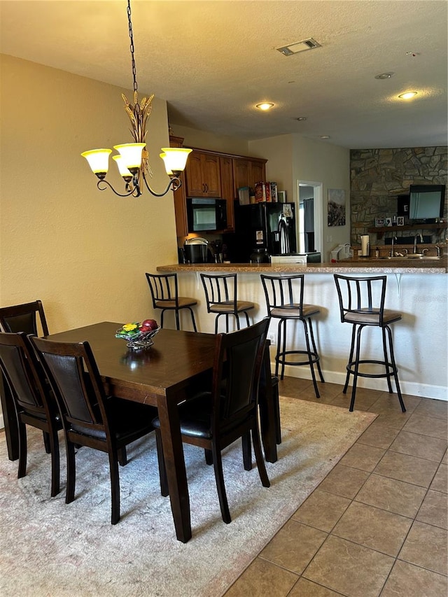 tiled dining space featuring a textured ceiling and an inviting chandelier