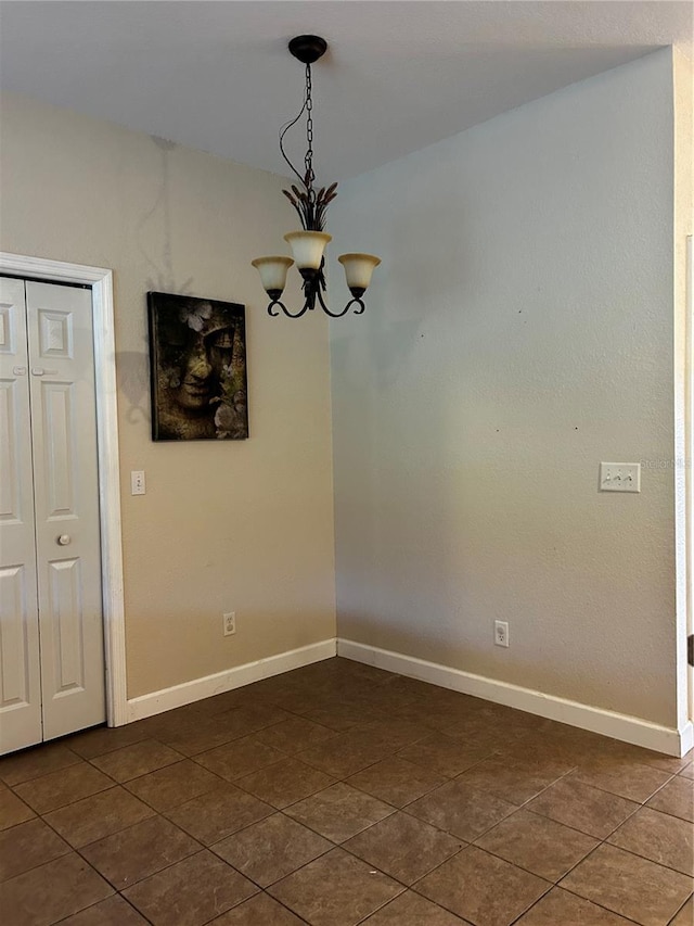 tiled empty room featuring a chandelier