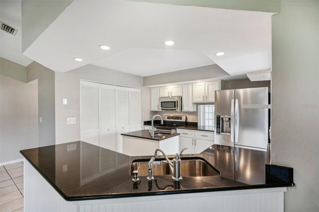 kitchen featuring light tile patterned floors, kitchen peninsula, white cabinets, appliances with stainless steel finishes, and sink