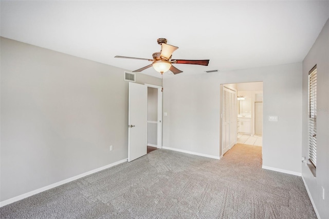 unfurnished bedroom with light carpet, connected bathroom, and ceiling fan