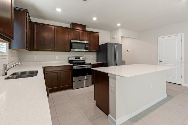 kitchen with stainless steel appliances, sink, light tile patterned floors, dark brown cabinetry, and a kitchen island