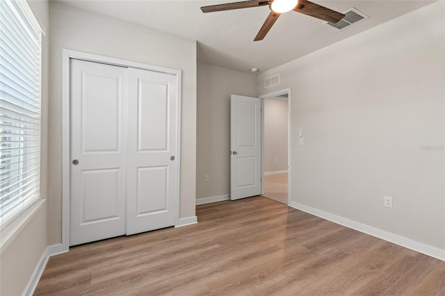 unfurnished bedroom with wood-type flooring, multiple windows, a closet, and ceiling fan