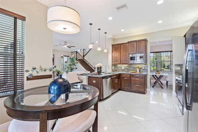 kitchen featuring appliances with stainless steel finishes, ornamental molding, decorative backsplash, decorative light fixtures, and kitchen peninsula