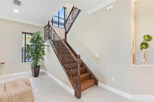 stairway with crown molding and tile patterned floors