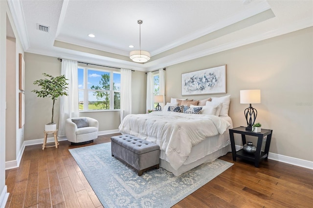 bedroom with crown molding, dark hardwood / wood-style floors, and a raised ceiling