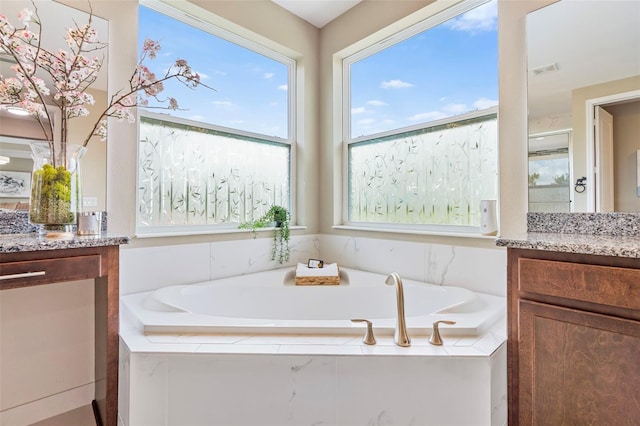 bathroom with vanity and tiled bath