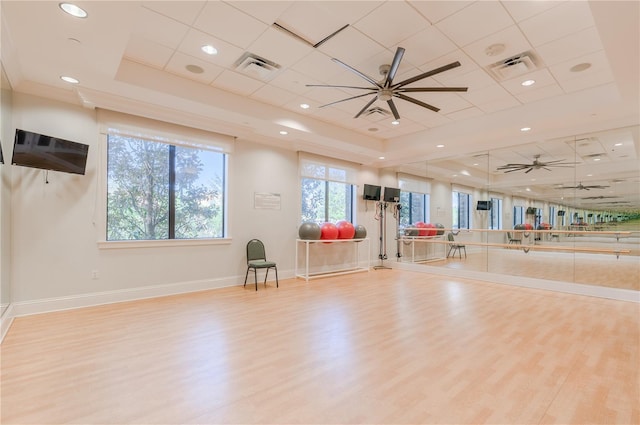 exercise area featuring crown molding, ceiling fan, a tray ceiling, and light hardwood / wood-style floors